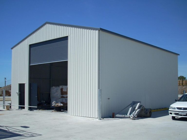 Big white steel sheds with a single-door rollup and a personnel door. This steel shed is made by Global Sheds Australia using Colorbond Steel and BlueScope steel. High quality, fully customisable steel sheds that can withstand harsh Australian weather. Built to last.